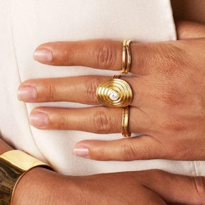 Macro view of gold stainless steel ring set with oval gemstone and wavy thin bands