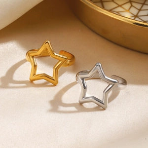 Minimalist gold and silver stainless steel star rings on a beige textured background