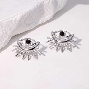 Silver devil eye stud earrings with black center stone on a minimalist stone background