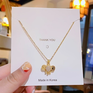 Elegant gold titanium elephant necklace featuring sparkling white zircon pendant on card