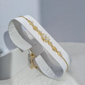 Detail of adjustable gold clover bracelet featuring white cat-eye stones and zircons
