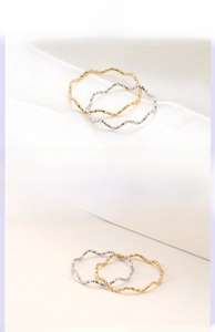 Detail view of wavy titanium steel rings in gold and silver showing textured surface