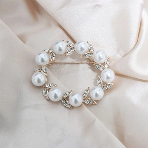 Macro shot of pearl wreath brooch with crystals on champagne silk background