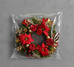Detailed view of the Christmas wreath in clear packaging showing red flowers and pine cones