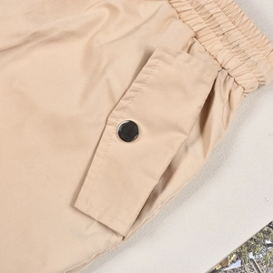 Detail of khaki twill cargo pants showing elastic waistband and metal snap pocket