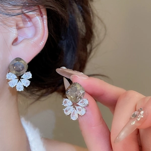 Detailed view of rhinestone drop earrings with smoky gray stones on a model's ear