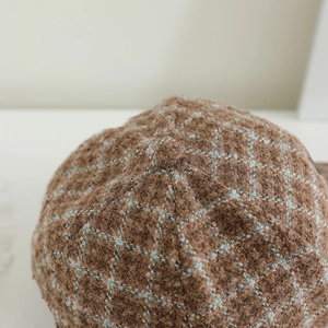 Détail de la texture du tissu en tweed à carreaux marron et bleu sur chapeau enfant