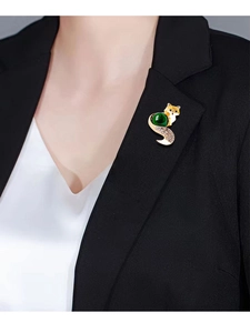 Close-up of vintage fox brooch with green gemstone on black blazer lapel