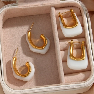 Detailed view of C-shaped and U-shaped acrylic enamel earrings in a soft pink velvet box
