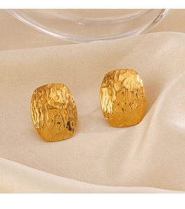 Detailed view of gold oval earrings with irregular lava texture on beige satin fabric