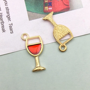 Detail of red enamel wine glass charm with golden metal frame and honeycomb texture back