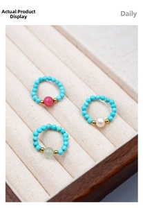 Detailed view of turquoise stretch rings with pearl accents in cream velvet tray