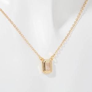 Close-up of a gold rectangle pendant necklace with a clear zircon on a white bust