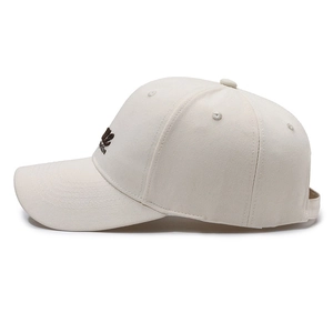 Beige baseball cap with brown letter embroidery and adjustable strap from a side view