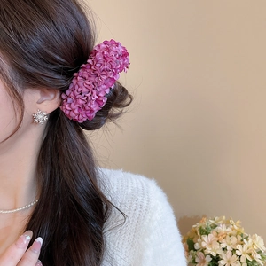 Close-up of a large purple fabric flower hair pin worn on a model for elegant styling