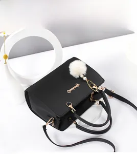 Detailed view of a black leather handbag with gold hardware and white faux fur keychain