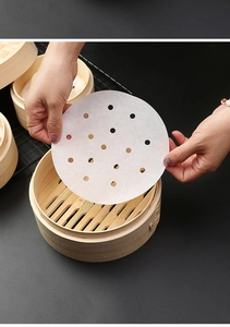 Close-up of placing round perforated steamer paper into a traditional bamboo steamer