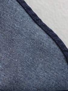 Vue macro détaillée de la texture du tissu denim bleu indigo avec tissage sergé et coutures
