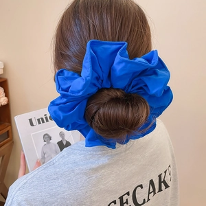 Détail d'un chouchou géant en tissu bleu roi porté sur un chignon élégant et chic
