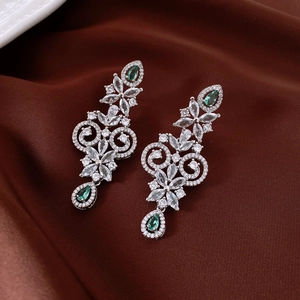Detail shot of silver drop earrings with green teardrop stones and zircon tassels