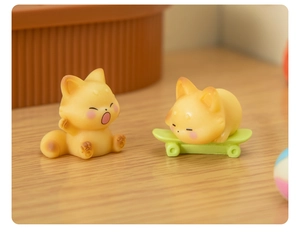 Macro detail of cute resin fox figurines: one yawning and one sleeping on a green skateboard