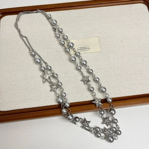 Detail of layered necklace with grey pearls and star pendants on a display tray