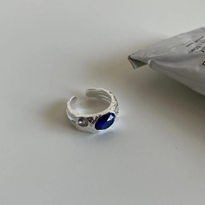 Macro detail of irregular hammered silver ring with oval blue stone and side zircon crystals