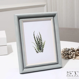 Minimalist ivory white photo frame with succulent art print on a clean white desk