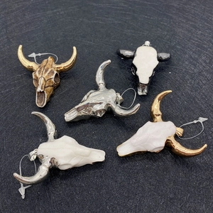 Detail of assorted bull skull pendants with acrylic stone in gold and silver finishes