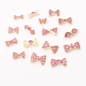 Detail view of 15 rose pink crystal bow nail art charms with golden alloy base