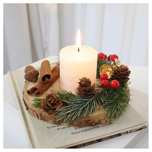 Macro detail of Christmas candle with pine cones, cinnamon sticks and golden bells on wood