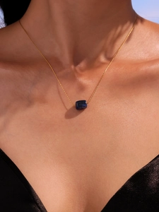 Close-up of gold chain necklace with a blue square stone pendant on model neck