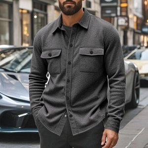 Detail of dark grey slim-fit jacket with buttoned chest pockets and durable fabric texture