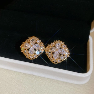 Detailed view of gold-plated floral earrings with sparkling zircon stones in a jewelry box