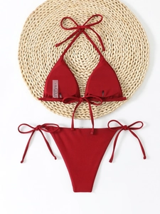 Detailed flat lay of a ribbed dark red triangle bikini set on a straw mat and white background