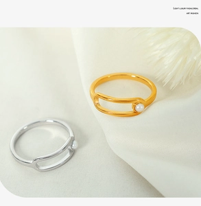 Detail of gold and silver open rings with pearls on elegant white fabric background