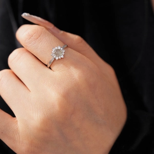 Close-up of vintage sunflower ring featuring green center stone and white zircon petals