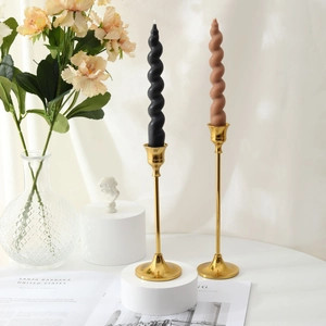 Detail of elegant black and brown spiral tapered candles on golden metal holders