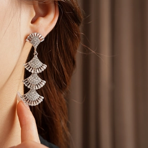 Close-up of sparkling silver tassel earrings with tiered fan shapes and zircon pavé