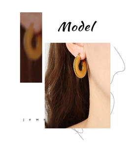 Close-up of gold-plated titanium U-shaped hoop earrings with textured grooved design