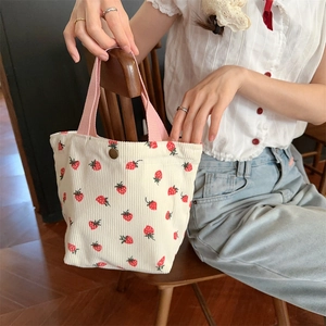 Détail d'un sac cabas en velours côtelé imprimé fraises avec poignée tissée rose élégante
