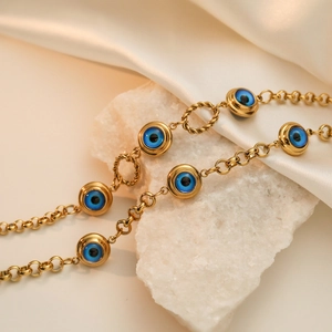 Minimalist gold plated stainless steel bracelet featuring blue evil eye charms on a stone