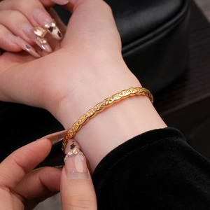 Gros plan d'un bracelet plaqué or 18k avec texture en losange et pierres sur poignet