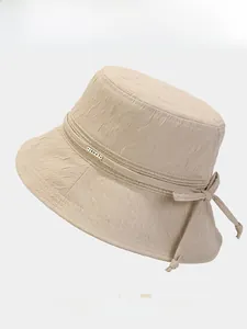 Détail d'un chapeau cloche plissé d'été avec nœud élégant et logo métallique