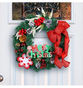Detail of Christmas wreath with red bow and Merry Christmas sign on white wooden door