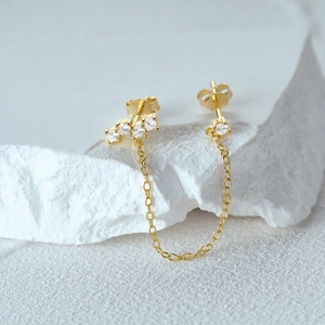 Macro detail of gold S925 silver chain earrings with cubic zirconia on stone background