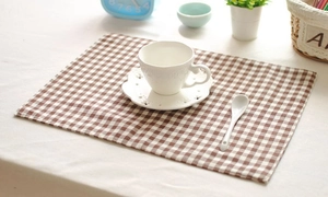 Detail of brown and white checkered linen placemat with coffee cup in a cozy cafe setting