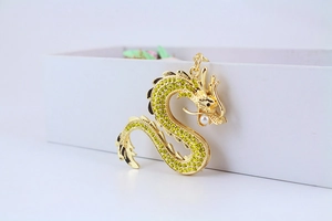 Détail d'un pendentif dragon doré avec strass jaunes et une perle blanche nacrée