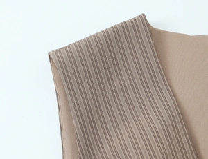 Close-up of the striped brown fabric texture and shoulder stitching detail on this dress