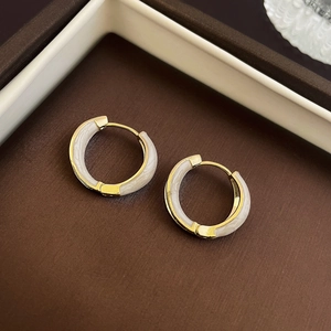 Detail view of gold-plated hoop earrings with white marble texture in a display box